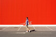 © VISTA by Westend61 - Young man carrying a ladder in front of a red wall