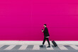 © VISTA by Westend61 - Young man with trolley walking along a pink wall, holding reusable cup