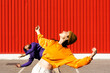 © VISTA by Westend61 - Young man and woman performing on road in front of red wall