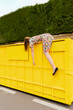 © VISTA by Westend61 - Exhausted woman hanging over edge of yellow container