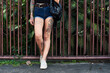 © VISTA by Westend61 - Legs of tattooed woman standing at garden fence
