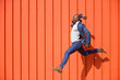 © VISTA by Westend61 - Businessman jumping in the air in front of orange wall