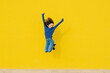 © VISTA by Westend61 - Young woman jumping in the air in front of yellow background
