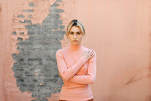 Portrait Of Blond Woman Wearing Pink Turtleneck Pullover In Front Of A Pink Wall