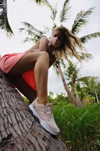 Young Beautiful Girl In Pink Skirt Wearing Fancy Nike Sport Sneakers In The Against Coronovirus Mask Near Palm Tree In Thailand