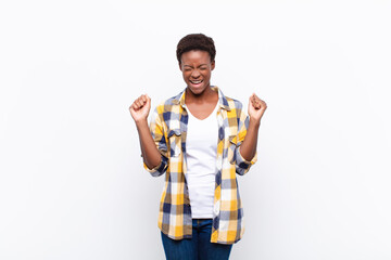 young pretty black womanlooking extremely happy and surprised, celebrating success, shouting and jumping