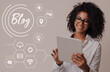 © Prostock-studio - African American girl using tablet computer on grey background, collage with word BLOG and web icons