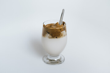 Dalgona Coffee with spoon in a clear glass on a white background. 