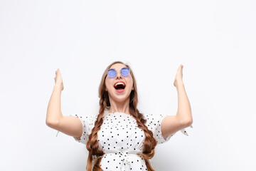 Wall Mural - yound blonde woman feeling happy, amazed, lucky and surprised, celebrating victory with both hands up in the air against white wall