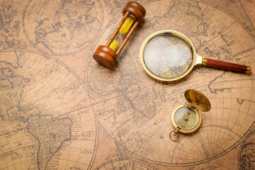 old compass , magnifying glass and sand clock on vintage map