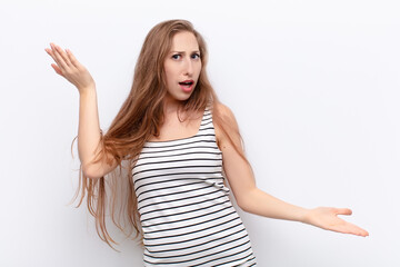 Wall Mural - yound blonde woman shrugging with a dumb, crazy, confused, puzzled expression, feeling annoyed and clueless against white wall