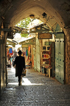 Jerusalem/ Israel -  An Orthodox Jew Wearing A Traditional Black Top Hat Is Walking Along A Cobbled Pavement Of The Old City Market