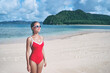 © Loginova - Enjoying suntan and vacation. Outdoor portrait of pretty young woman in red swimsuit on beautiful tropical beach.