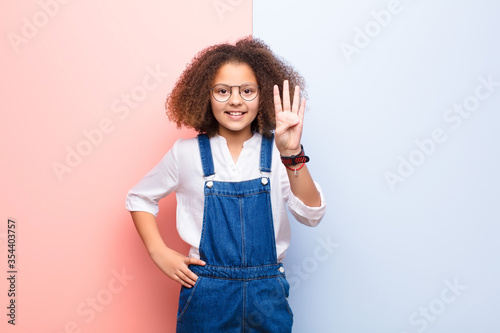 Fotomural african american little girl smiling and looking friendly, showing number four o