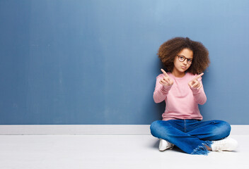 Wall Mural - african american little girl feeling provocative, aggressive and obscene, flipping the middle finger, with a rebellious attitude sitting on the floor