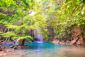  Beautiful waterfall in tropical jungle forest with big green tree and emerald lake on foreground. Nature landscape of Erawan National park, Kanchanaburi, Thailand