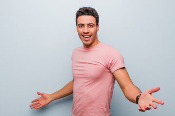 Wall Mural - young arabian man looking happy, arrogant, proud and self satisfied, feeling like a number one against gray wall