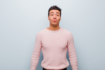 Wall Mural - young arabian man pressing lips together with a cute, fun, happy, lovely expression, sending a kiss against gray wall