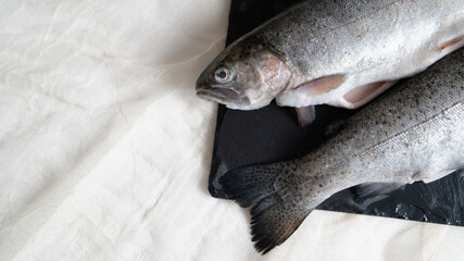 two gutted rainbow trout fish on a black stone board. fish prepared for soup. fish soup ingredient. gutting the fish