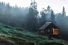 Small Old Wooden House In Foggy Forest. Mountains Scenery. Nature Conceptual Image.