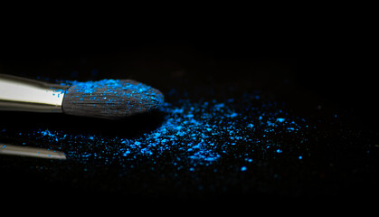 Blue powder and a brush on a black background