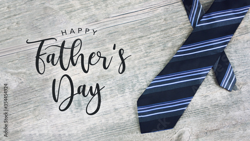 Happy Father\'s Day Greeting Card Calligraphy Text with Striped Neck Tie Over Light Wood Background