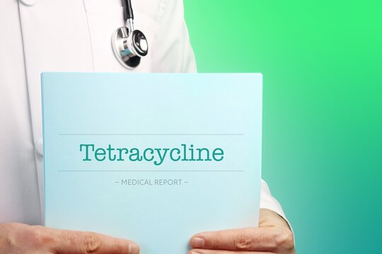 Tetracycline. Doctor (male) with stethoscope holds medical report in his hands. Cutout. Green turquoise background. Text is on the documents. Healthcare/Medicine