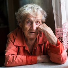 Wall Mural - Portrait of an elderly woman pensioner sitting at kitchen in her home.