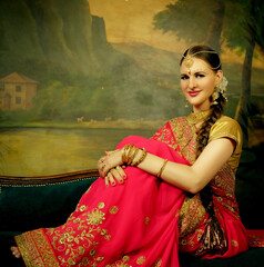 Portrait smiling of beautiful indian girl at home. Young woman model with golden jewelry set .