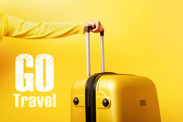 woman holding yellow suitcase in hand over yellow background, go travel concept