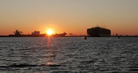 Wall Mural - Cargo ship entering the Port of Rotterdam during twilight light glow after sunset. Container ships and tankers