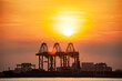Crane for shipping container carrier with sunrise background 