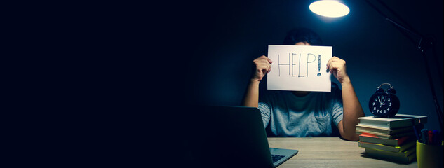 A man sitting and working at home late at night He has accumulated stress, wants to ask for help. Concept working from home, social distance. New Normal. copy space