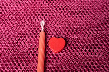 Sticker - High angle shot of a red candle and a heart-shaped object on a pink surface