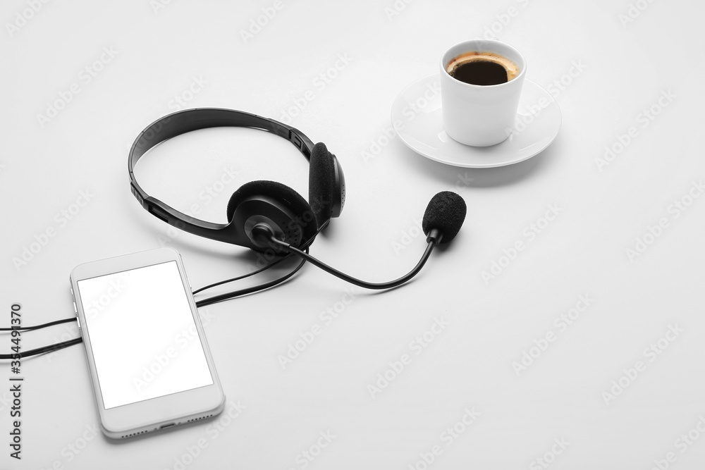 Headset, mobile phone and coffee on white background