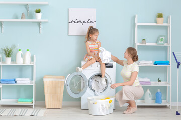 Mother and little daughter doing laundry at home