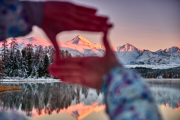 Woman is pulling her hands to mountain. she looks through her thumbs