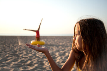 Young girl dream to be gymnast and holdin in hands. Sport mood in the beach. two girls in vacation have fun in sand shore of sea