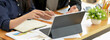 © bongkarn - Businesswoman working with tablet, notebook and paperwork on wooden office desk