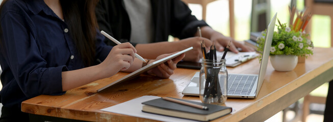 Businesspeople working together with tablet, laptop, stationery and paperwork on office desk