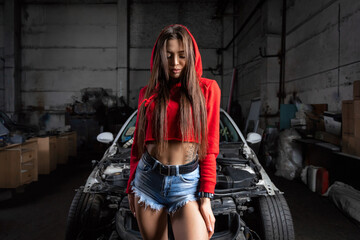 Portrait woman in jeans shorts and top posing next to a  car in the garage, in background old car  Creative Colorful Bright neon Portrait .Design Car workshop art concept