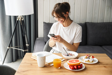 Sticker - Photo of smiling woman typing on cellphone while having breakfast