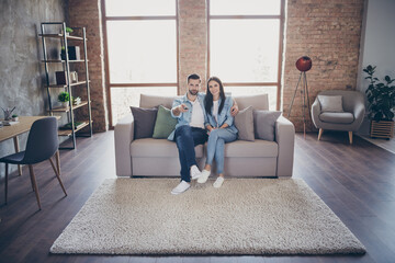 Sticker - Full length photo of married couple focused man try find romantic film hug embrace joyful woman hold remote control sit divan in house indoors