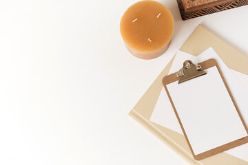 Wall Mural - Blank paper sheet clipboard tablet pad with mock up copy space. Beautiful home office table desk workspace with wooden casket, candle, albums. Flat lay, top view art concept