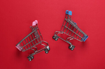 Wall Mural - Two mini supermarket trolleys on red background. Shopping concept. Top view. Minimalism