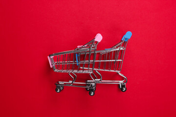 Wall Mural - Two mini supermarket trolleys on red background. Shopping concept. Top view. Minimalism