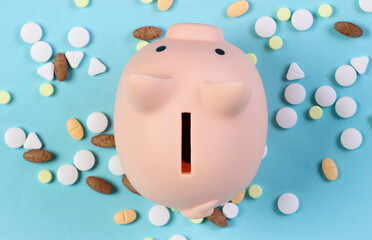 Piggy bank with pills on blue background. Top view