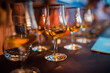 Glasses with brandy stand in a row. Blurred background, warm tinted. Tasting glasses with aged french cognac brandy