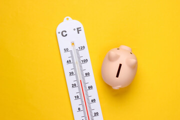 piggy bank and weather thermometer on yellow background. minimalistic studio shot. overhead view. fl