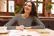 © Drobot Dean - Image of student woman doing homework and smiling while drinking tea